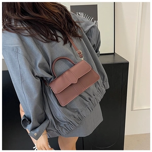 Modèle portant un sac bandoulière bordeaux en similicuir avec poignée arrondie en intérieur