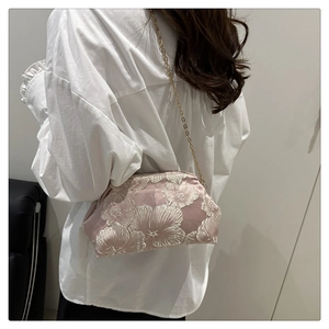 Detail of pink embroidered floral bucket bag with chain strap worn by a model