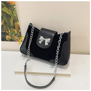 Detail of black saddle bag with silver metal bow and suede leather patchwork texture