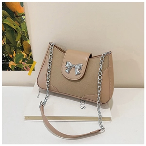 Close-up of khaki patchwork saddle bag with silver bow buckle and metal chain strap