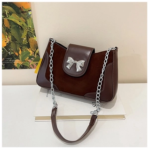 Detail view of vintage brown saddle bag with silver metal bow and chain strap