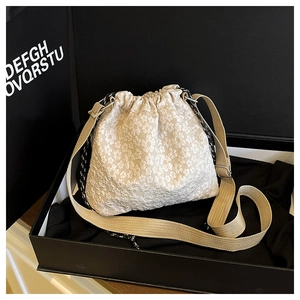 Detailed close-up of cream floral jacquard bucket bag with adjustable khaki woven strap