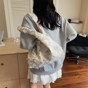 Grand sac cabas crème à motif papillon bleu et détails effilochés porté par mannequin