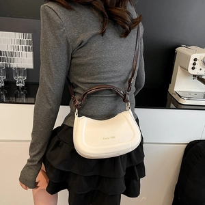 Minimalist cream crescent shoulder bag with dark brown twisted handle and gold hardware