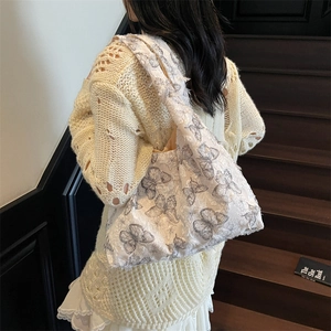 Sac fourre-tout en toile blanche à imprimé papillon gris porté par un mannequin en escalier