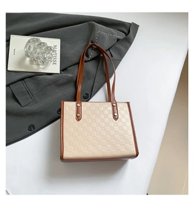 Detail of checkered tote bag with brown leather handles and vintage metal rivets
