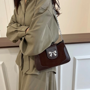 Minimalist dark brown saddle bag with suede leather and a silver bow on a chain strap