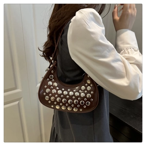Detail of silver rivets on dark brown leather crescent moon shoulder bag in retro style