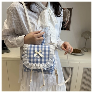 Detail of blue gingham mini backpack with white lace, heart buttons, and bow decoration