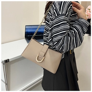 Dettaglio borsa a spalla in pelle beige con fibbia a D dorata e tracolla a catena