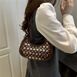 Sac hobo croissant marron avec rivets argentés porté à l'épaule style décontracté