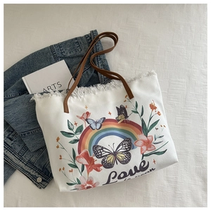 Détail du sac cabas en toile avec imprimé papillon arc-en-ciel, franges et bandoulière cuir
