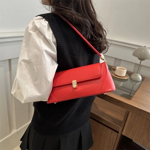 Red leather shoulder bag with vintage gold clasp on a model in a minimalist home setting