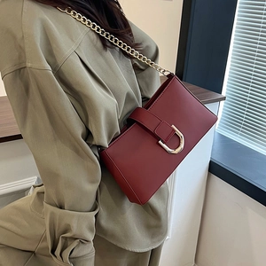 Borsa a tracolla bordeaux retrò con fibbia a D dorata e catena indossata da un modello