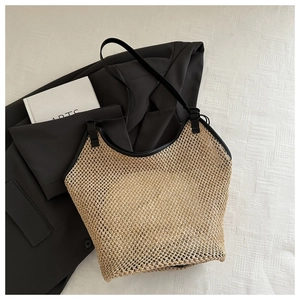 Détail d'un grand sac fourre-tout en paille beige avec bandoulières en similicuir noir