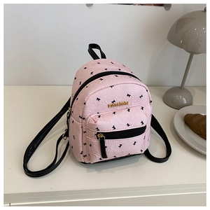 Detail of pink mini backpack with bow prints, gold fashion logo and quilted texture