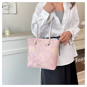Gros plan détaillé d'un sac cabas fleuri rose avec ferrures argentées et anses en cuir