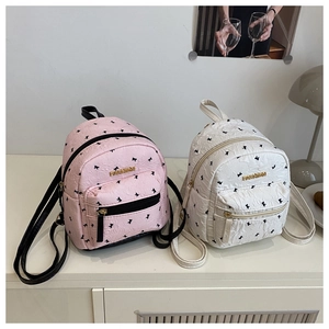 Detail of pink and white mini backpacks with bow prints and golden fashion logo