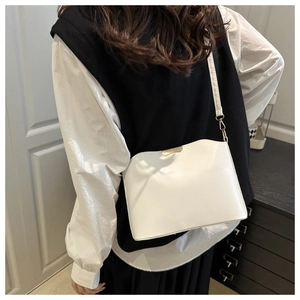 Détail du sac coquillage blanc avec boucles dorées porté en bandoulière pour femme