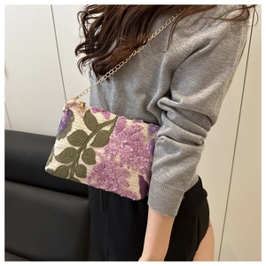 Détail de la pochette brodée de fleurs avec paillettes mauves et chaîne dorée sur mannequin