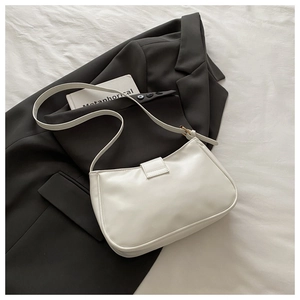 Detail of white PU leather crescent bag on gray suit with adjustable shoulder strap