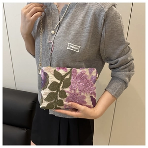 Détail de broderie florale à paillettes sur sac crème avec bandoulière en chaîne dorée