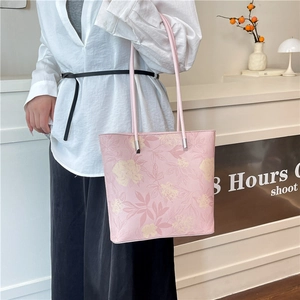 Grand sac cabas rose à motif floral avec longues anses, porté par un mannequin élégant
