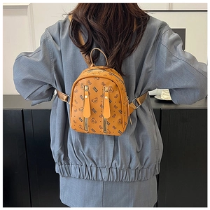 Detail view of mustard yellow backpack with bear print and golden zippers on model