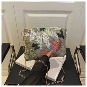 Détail de la broderie à paillettes et chaîne dorée sur une pochette de soirée chic