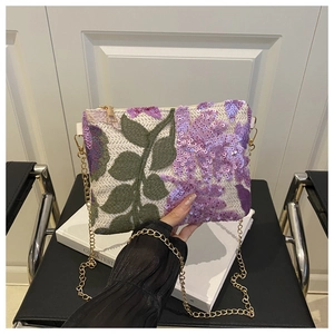 Détail de la broderie à paillettes et de la chaîne dorée sur cette pochette ivoire chic