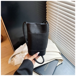 Detail of black pebbled leather texture on a compact vertical crossbody phone bag