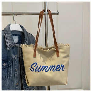 Détail du cabas en toile beige avec franges, broderie Summer bleue et anses en cuir