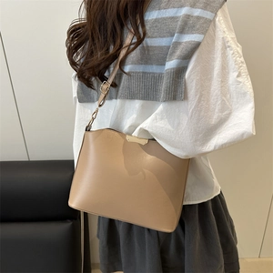 Sac coquille beige minimaliste avec large bandoulière et décor doré sur modèle