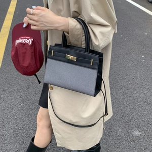 Detail of a two-tone leather handbag with woven texture and elegant metal clasp
