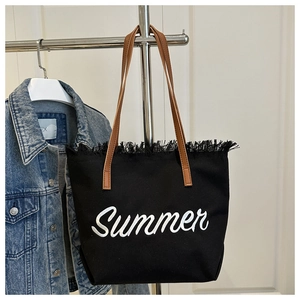 Détail du sac cabas en toile noire avec broderie Summer blanche et bords effilochés