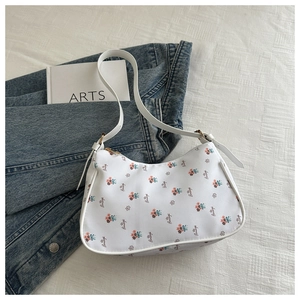 Detail of white hobo bag with floral prints, French script, and leather strap