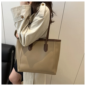 Detail of minimalist tote bag with beige PU leather and brown contrast shoulder straps