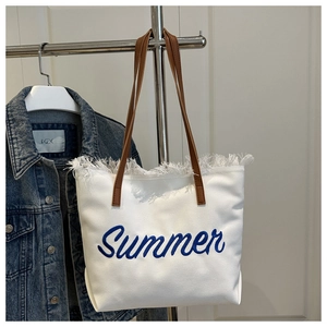 Détail du sac cabas en toile blanche avec broderie Summer bleue et bords à franges