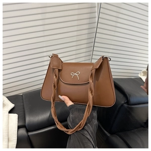 Dettaglio della borsa in pelle PU marrone caffè con fiocco argento e tracolle intrecciate