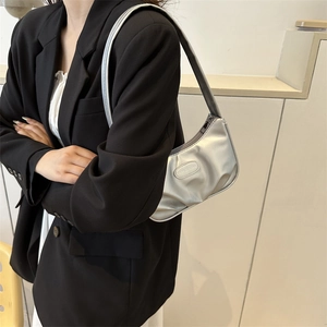 Silberne Falten-Schultertasche mit Modeetikett an Model mit schwarzem Anzug getragen