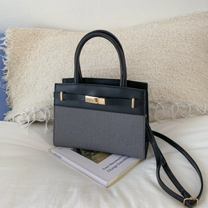 Detail of color-block tote bag with gold metal buckle on white bedding scene
