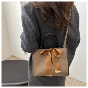Détail du sac bandoulière kaki avec un grand nœud décoratif et poignée tissée noire