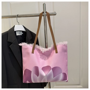 Detail of pink canvas tote bag featuring raw frayed edges and brown leather straps