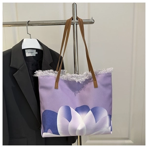 Detail showing purple canvas tote bag with floral print and frayed fringe edge finish