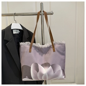 Detail of purple tote bag with abstract white petals, fringe edge and brown leather straps