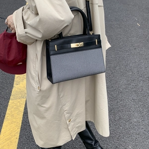 Chic color-block handbag with gold twist lock and shoulder strap on a beige coat model