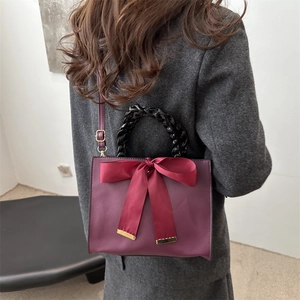Sac à main bordeaux élégant avec grand nœud en satin rouge et poignée tressée noire