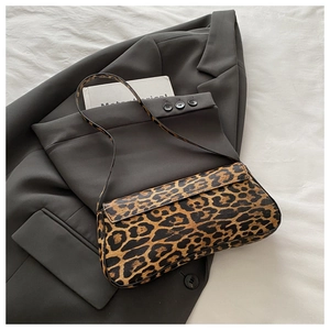 Detail einer trendigen Baguette-Tasche mit Leopardenmuster auf grauem Blazer