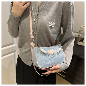 Detail of mini crossbody bag in glittery blue fabric with pink leather straps and pearl chain