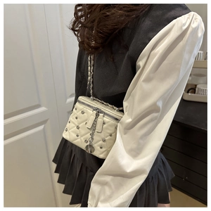 Detail of white quilted box bag featuring silver studs and metallic chain strap